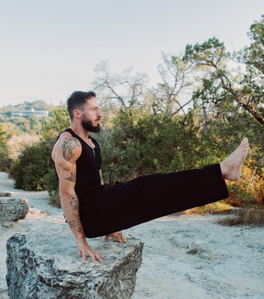 Tom Fysh holding an L-sit on a rock